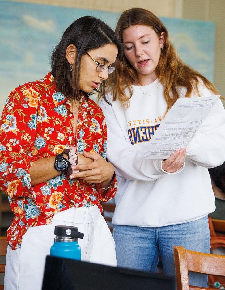 two pitzer students look over a paper