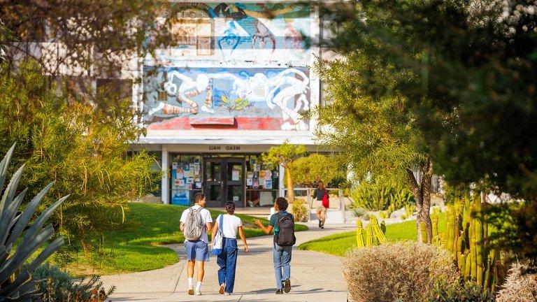 three students walk towards mead hall